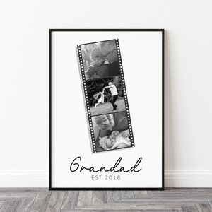 May include: Black and white framed print featuring a film strip of three family photos. The word "Grandad" is written in cursive below the photos, with "EST 2018" underneath. The frame is black, and the background is white.