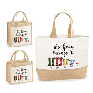 May include: Two tote bags with a jute bottom and a white canvas top. The bags have a black print that says "This Gran Belongs To" with a row of colorful rain boots and names underneath. The smaller bag has the names Phil, Grace, Lily, Harry, and Tilly. The larger bag has the names Phil, Grace, Lily, Harry, and Tilly.
