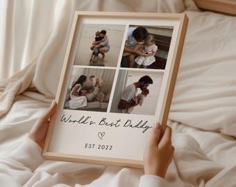 May include: A framed photo collage with four family photos. The frame is light wood. The text "World's Best Daddy" is written in script font, with a heart symbol and "EST 2022" below. The photos show family moments.
