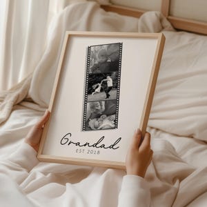 May include: A framed black and white photo collage with three images. The frame is light wood. The text "Grandad EST 2018" is written in a script font at the bottom of the frame.