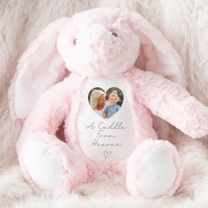 May include: Pink plush bunny with a white heart-shaped patch. The patch has a photo of a woman and a child and the text "A Cuddle From Heaven".