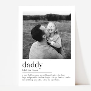 K&ouml;nnte beinhalten: Schwarz-Wei&szlig;-Druck mit einem Vater, der sein lachendes Kind k&uuml;sst. Das Wort "daddy" ist unter dem Bild abgebildet, zusammen mit einer Definition, die einen liebevollen Vater beschreibt. Der Hintergrund zeigt eine verschwommene Szene im Freien.