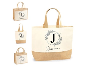 May include: Three tote bags made of natural burlap and canvas with a floral design and the letter J in a circle. The largest bag has the name Jessica printed below the design.