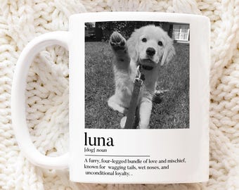 May include: White ceramic mug featuring a black and white photo of a puppy raising its paw. The mug includes the name "luna" and a definition of a dog. The mug is on a white knitted surface.