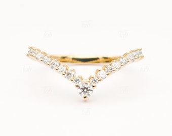 May include: A gold ring with a V-shaped band of small diamonds. The ring has a larger diamond at the point of the V.
