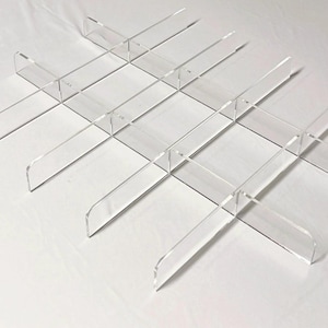 Puede incluir: Un juego de divisores de acr&iacute;lico transparente para organizar estantes. Los divisores tienen forma de 'L' y se pueden usar para crear m&uacute;ltiples compartimentos en un estante.