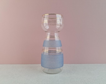 May include: A clear glass vase with a flared top and a tapered body. The vase features two horizontal bands of textured, light blue frosted glass, each accented by thin, horizontal gold-coloured stripes encircling the neck and midsection.