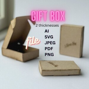 May include: Three small, open and closed, brown cardboard gift boxes. The text "GIFT BOX" is in pink, with "file" in a cursive font. File formats listed are AI, SVG, JPEG, PDF, and PNG. The boxes are on a white surface.