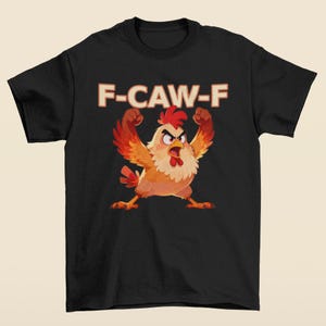 May include: Black t-shirt featuring a cartoon chicken with raised fists and an angry expression. The text "F-CAW-F" is printed above the chicken in a bold, retro font. The chicken is primarily orange, red, and yellow.