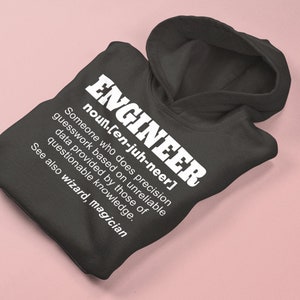 May include: A dark grey hoodie with a white print that reads "ENGINEER noun.[en-juh-neer] Someone who does precision guesswork based on unreliable data provided by those of questionable knowledge. See also wizard, magician"