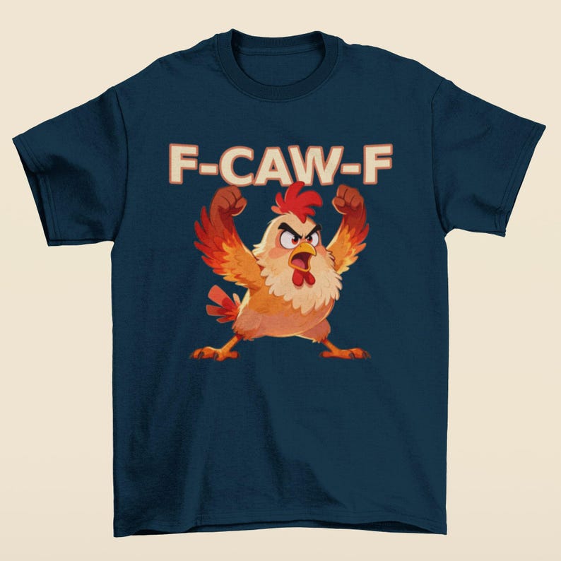 May include: Navy blue t-shirt featuring a cartoon chicken with raised wings and an angry expression. The text "F-CAW-F" is printed above the chicken in a retro font. The chicken is primarily orange, red, and yellow.