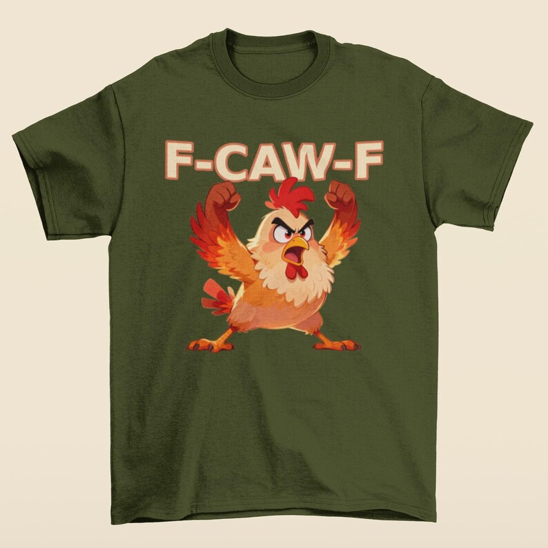 May include: Olive green t-shirt featuring a cartoon chicken with raised fists and an angry expression. The text "F-CAW-F" is printed above the chicken in a retro font. The chicken has red, orange, and yellow feathers.