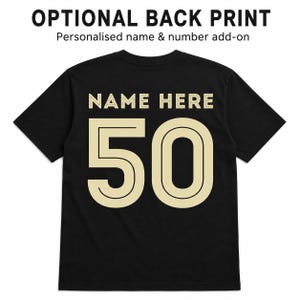 May include: A black short-sleeved t-shirt featuring the text OPTIONAL BACK PRINT and Personalised name & number add-on at the top. The back of the shirt displays the text NAME HERE in beige above the large beige number 50 with a black outline.
