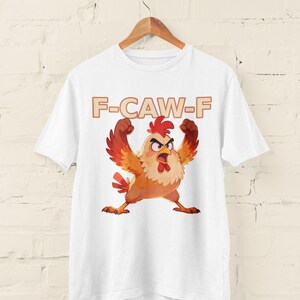 May include: White t-shirt featuring a cartoon chicken with an angry expression, wings raised, and the text "F-CAW-F" in a brown font. The chicken is primarily orange, red, and yellow.