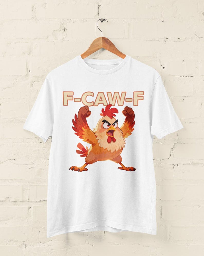 May include: White t-shirt featuring a cartoon chicken with an angry expression, wings raised, and the text "F-CAW-F" in a brown font. The chicken is primarily orange, red, and yellow.