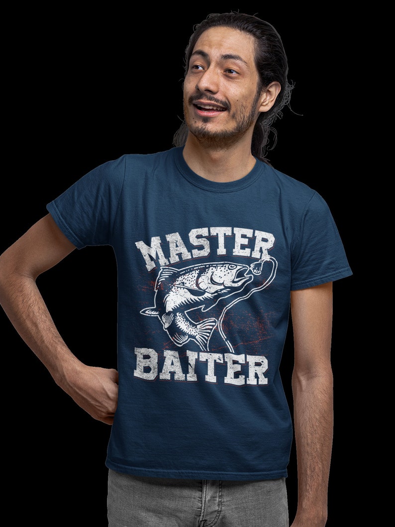 May include: A navy blue short-sleeved t-shirt featuring a white graphic of a fish on a fishing line. The text "MASTER BAITER" is printed in a distressed white font above and below the fish illustration, with subtle red accents.