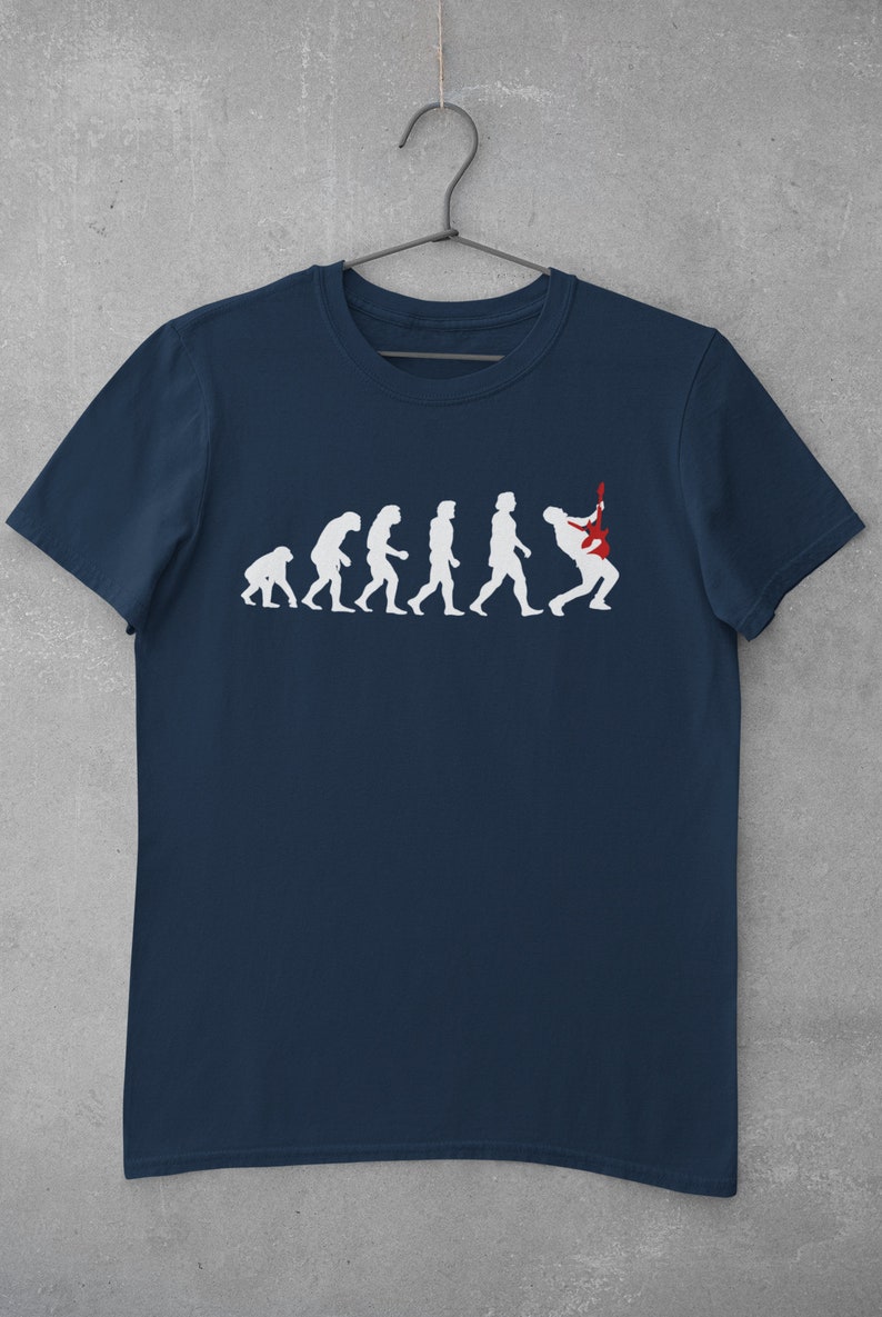 May include: A navy blue t-shirt featuring a white graphic of the evolution of man, culminating in a person playing an electric guitar.