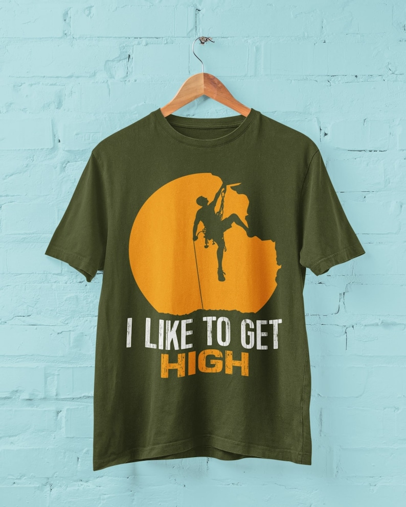 May include: A green t-shirt with a silhouette of a person rock climbing on a yellow sun. The text "I like to get HIGH" is printed below the image.