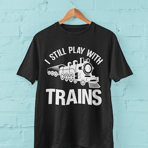 May include: Black t-shirt with a white graphic of a train and the text "I still play with trains".