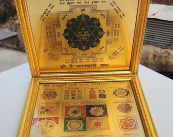 Puede incluir: Una caja de dos partes con un marco dorado y un diseño decorativo. La parte superior presenta un yantra verde y dorado con el texto "श्री सरस्वती यन्त्रम्" y "ॐ ऐं सरस्वत्यै नमः". La parte inferior presenta una cuadrícula de 12 yantras más pequeños con el texto "श्री सम्पूर्ण सर्व कष्ट निवारण यन्त्रम्" y "श्री सम्पूर्ण महालक्ष्मी महायन्त्रम्".