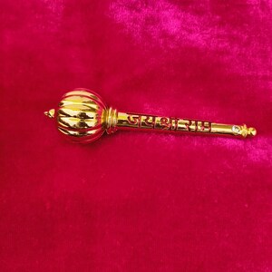 Op de afbeelding: Een gouden metalen knots met een ronde kop en een lange steel. De steel is gegraveerd met de tekst "जय श्री राम".