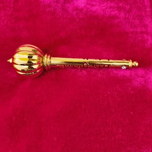 Op de afbeelding: Een gouden metalen sleutel met een rond, versierd hoofd. De sleutel heeft een decoratief ontwerp op de schacht.