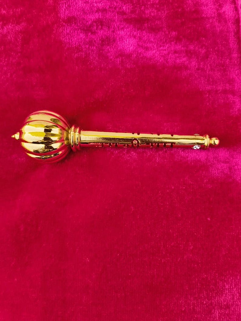 Op de afbeelding: Een gouden metalen sleutel met een rond, versierd hoofd. De sleutel heeft een decoratief ontwerp op de schacht.