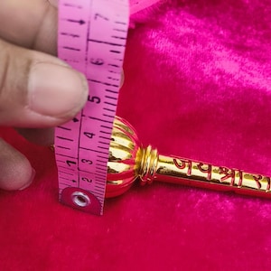 Op de afbeelding: Een gouden metalen ceremoni&euml;le knots met een ronde kop en een handvat met de tekst "जय श्री राम" erop.