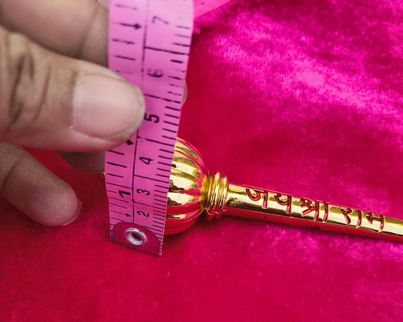 Op de afbeelding: Een gouden metalen ceremoni&euml;le knots met een ronde kop en een handvat met de tekst "जय श्री राम" erop.