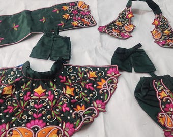 May include: A set of green clothing with floral embroidery in shades of orange, pink, and yellow. The set includes a skirt, a top, a pair of pants, a shawl, and a necklace.