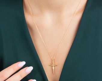 May include: A gold chain necklace with a sword-shaped pendant. The pendant has a small diamond-like stone in the center.
