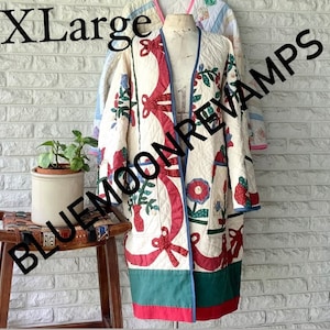 May include: A white quilted jacket with red, green, and blue floral patterns. The jacket has a long, loose fit and a V-neck. The text "XL" and "BLUEMOONREVAMPS" is visible on the image.
