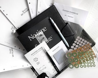 May include: An assortment of planner accessories, including a black leather-bound planner, stickers, dividers, and notepaper. The planner is open to reveal a pen and a page with the words "No time to waste." Other items include round and square stickers.