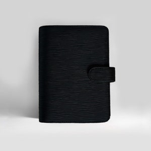 Puede incluir: Planificador de cuero negro con una superficie texturizada y un cierre de solapa.