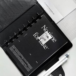 May include: Black planner dividers with the text "PLANNER DIVIDERS A5" and "MY ROADMAP" on the top. The dividers are in a black leather planner with a clear plastic sheet with the text "No time for fake" and "TOO BUSY".