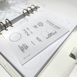 May include: A set of motivational stickers with white text on a white background. The stickers feature phrases like "When you're ready, begin again", "Success doesn't come to you, you go to it", and "It's time to start believing in yourself".
