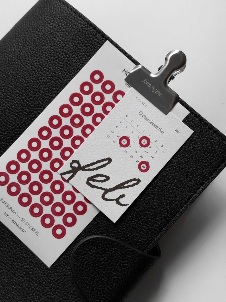 May include: A white sticker sheet with 60 burgundy circular stickers, featuring the text "BURGUNDY - 60 STICKERS" and "MY ROADMAP". A small calendar card for February 2027 is clipped to the sheet with a silver metal clip labeled "form & flow".