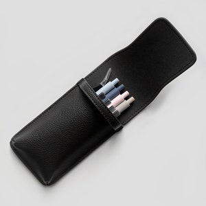 Op de afbeelding: Een zwart leren potlood etui met een klep sluiting, open om een ​​set kleurpotloden te laten zien.