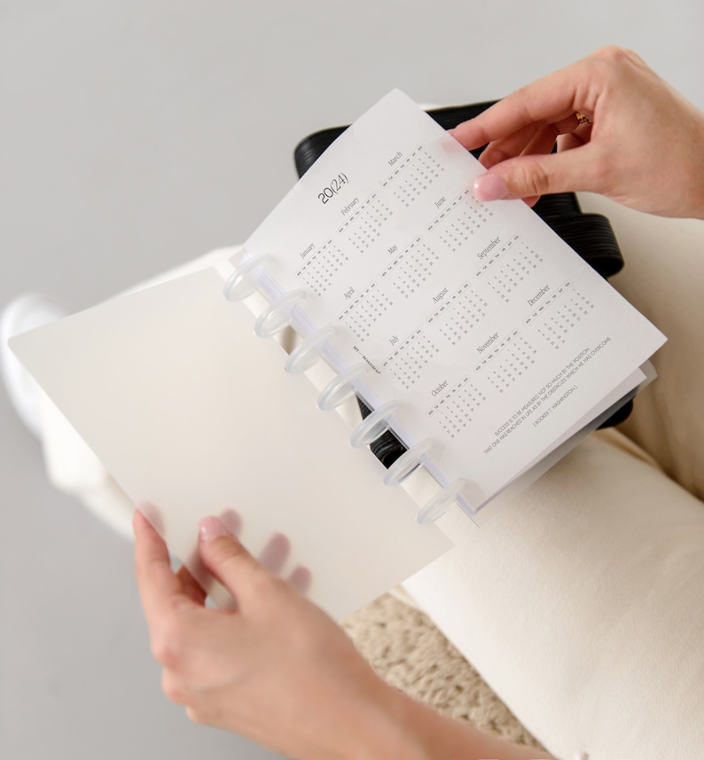 Pu&ograve; includere: Un'agenda a dischi con una copertina traslucida satinata e una pagina di calendario 2024. Il calendario mostra tutti i dodici mesi con testo nero e include una citazione di Booker T. Washington nell'angolo in basso a destra della pagina.
