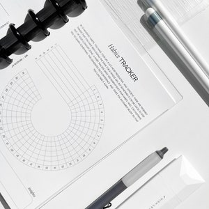 May include: A white habit tracker with a black and white grid pattern and the text "Habits TRACKER" at the top. The text below the title reads "By changing habits, you make your life a lot more productive and efficient. There are probably things that you have been doing the same for a whole life, but sometimes it can be good to step out of your comfort zone. A habit tracker gives you insight into your habits and can motivate you to learn something. This generates self-confidence and gives you an energy boost so that you can take it again."