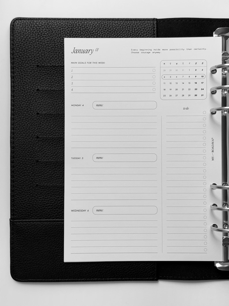 May include: A black leather-textured binder containing a white planner insert. The page features a January calendar, a section for main goals, and daily planning fields for Monday, Tuesday, and Wednesday with memo boxes and a to-do list column.