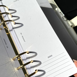 May include: Open planner with gold-colored rings and white paper. The pages are labeled "Goals and important", "MY - ROADMAP", and "notes". The planner is open to a page with three boxes and lined spaces for notes.