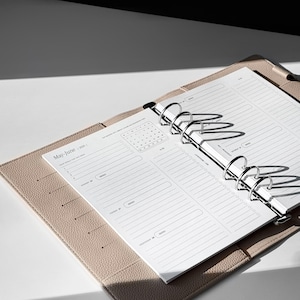 May include: A beige leather bound planner with silver rings and a white page open to the May-June 2020 calendar section. The page has a monthly calendar and a daily planner section with lines for writing.
