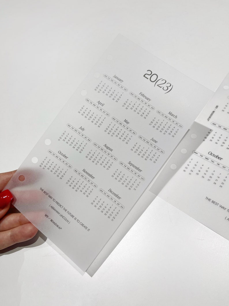 Pu&ograve; includere: Un inserto per agenda traslucido e satinato con una panoramica del calendario 2023. La pagina include dodici griglie mensili, il testo 20(23), la citazione THE BEST WAY TO PREDICT THE FUTURE IS TO CREATE IT (ABRAHAM LINCOLN) e MY-ROADMAP.