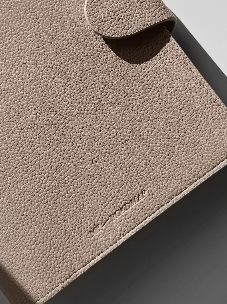 May include: A light beige leather notebook with the word "remarkable" embossed on the cover.