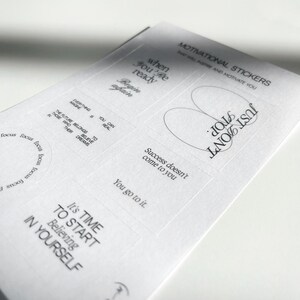 May include: A sheet of white paper with motivational stickers printed on it. The stickers feature inspirational quotes such as "When you're ready, begin again", "Just don't quit", "Success doesn't come to you, you go to it", "It's time to start believing in yourself", and "The future belongs to those who believe in their dreams".