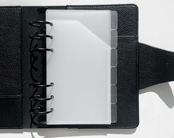 May include: Black leather bound planner with a clear plastic insert with dividers. The planner has a ring binding system.