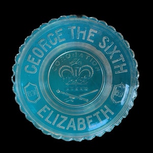 May include: A blue glass commemorative plate with a scalloped edge. The plate features the text "George The Sixth Coronation Elizabeth 1937" and a royal crest with a crown and scepter.