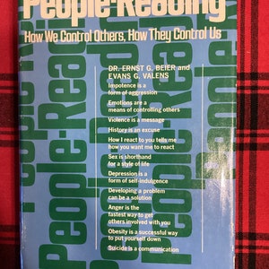 Könnte beinhalten: Ein blaues Buch mit dem Titel "People-Reading: How We Control Others, How They Control Us" und Text über menschliches Verhalten und Kommunikation. Der Buchumschlag zeigt den Titel in großen weißen Buchstaben und den Text in kleineren weißen Buchstaben.