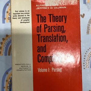 May include: A red and white book titled "The Theory of Parsing, Translation, and Compilation" by Jeffrey D. Ullman. The book is the first volume in a series on compiler development. The book is part of the Prentice-Hall Series in Automatic Computation.